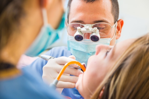 Dentista al lavoro con l&#39;assistente dentario che esamina i denti pazienti