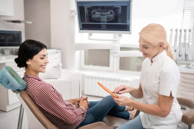 Dentista allegro con tablet in mano alla ricerca della data del nuovo appuntamento con il suo paziente