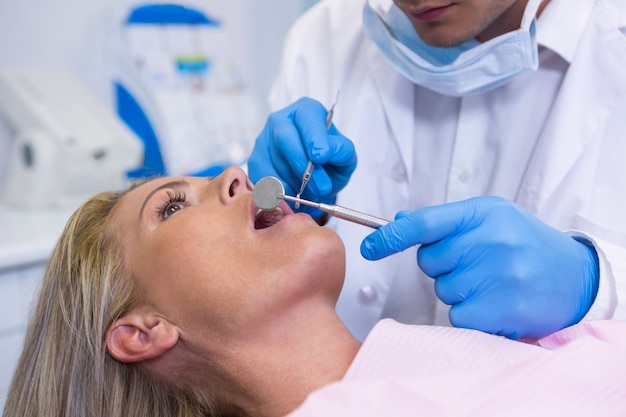 Dentista che esamina giovane donna alla clinica medica