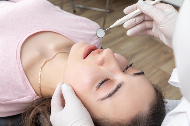 Dentista che esamina i denti del paziente con lo specchio dentale durante il controllo dentale