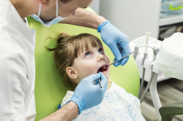 Dentista che esamina i denti della bambina in clinica Problema dentale