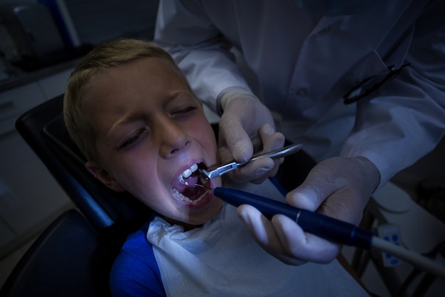 Dentista che esamina un giovane paziente con gli strumenti