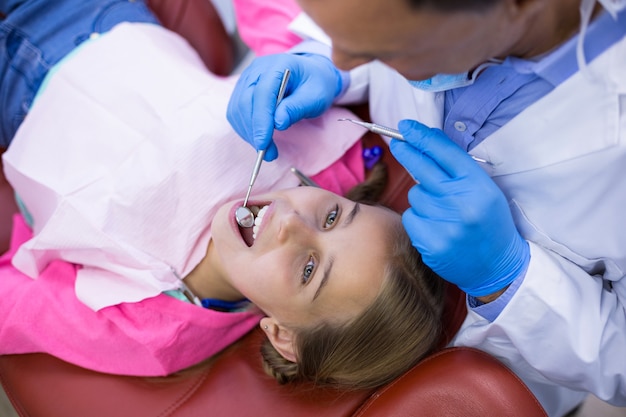 Dentista che esamina un giovane paziente con gli strumenti