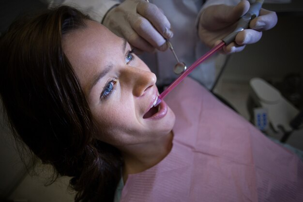 Dentista che esamina un paziente femminile con gli strumenti