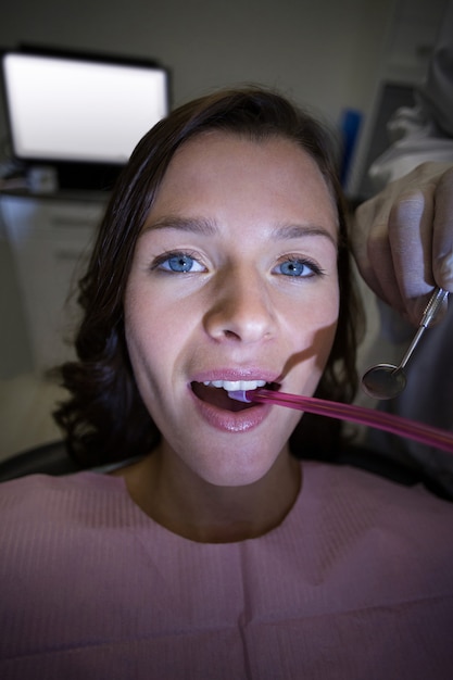 Dentista che esamina un paziente femminile con gli strumenti