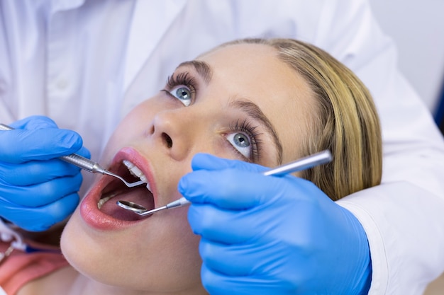 Dentista che esamina un paziente femminile con gli strumenti