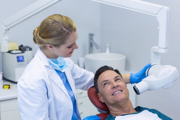 Dentista che esamina un paziente maschio con lo strumento dentale