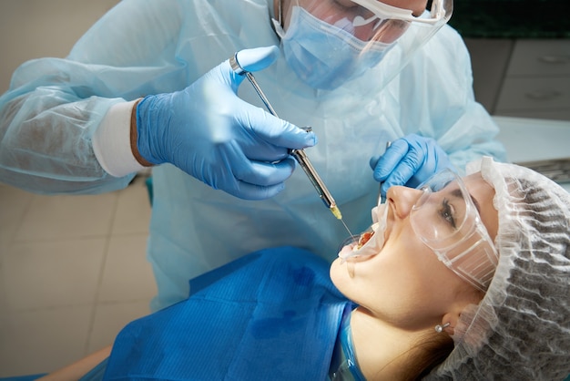 Dentista che fa colpo di anestesia locale prima dell'intervento chirurgico. Paziente che visita uno studio dentistico