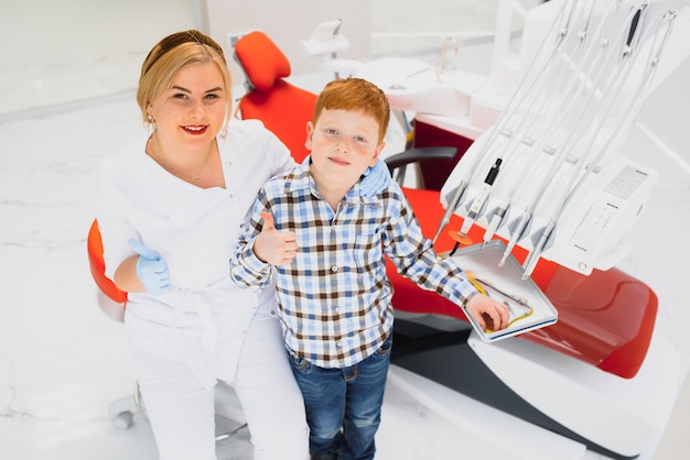 Dentista che indossa la maschera. Dentista bambino dai capelli rossi che indossa la maschera esaminando ragazzo carino