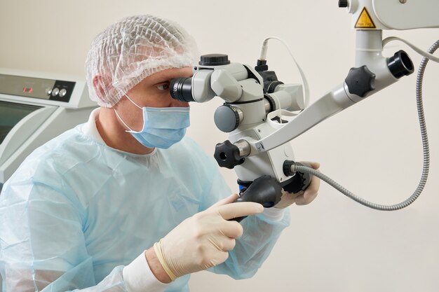 Dentista che lavora con microscopio dentale e paziente presso la moderna clinica dentista