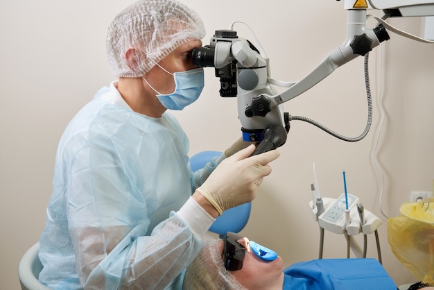 Dentista che lavora con microscopio dentale e paziente presso la moderna clinica dentista