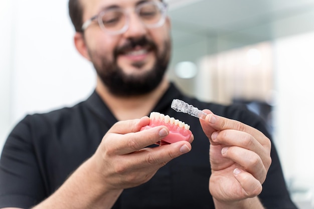 dentista che mostra allineatori chiari sulla mascella umana artificiale che presenta una correzione dei denti innovativa
