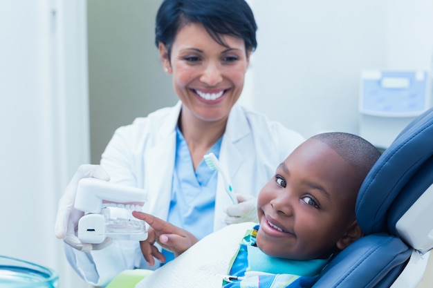 Dentista che mostra i denti della protesi del ragazzo