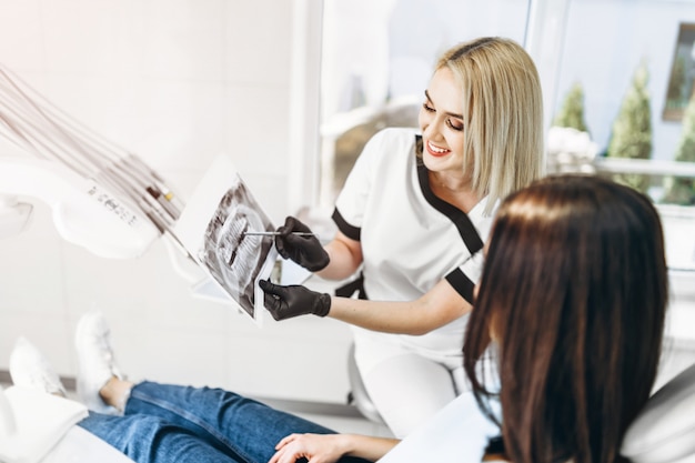 Dentista che mostra i raggi x per il paziente e che spiega il piano di trattamento.