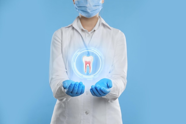 Dentista che mostra il modello virtuale del dente su sfondo azzurro primo piano