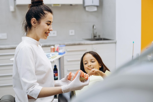 Dentista che mostra le parentesi graffe sulla mascella falsa a un paziente bambino