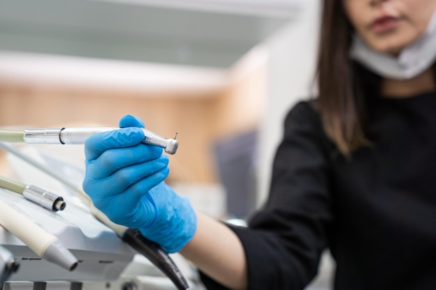 Dentista che prendo il trapano del quadro strumenti della macchina dentale per lavorare con il paziente in stomatologia