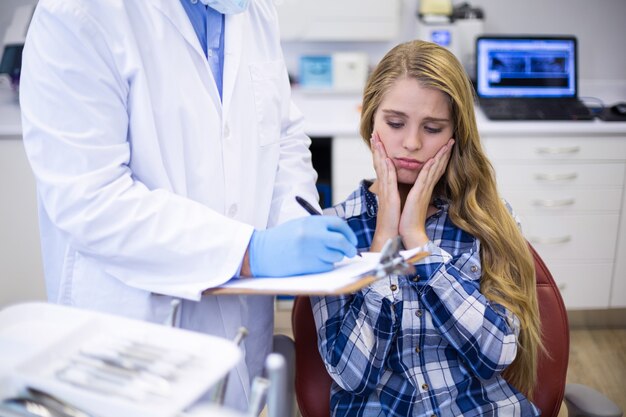 Dentista che prepara il rapporto dentale del paziente femminile