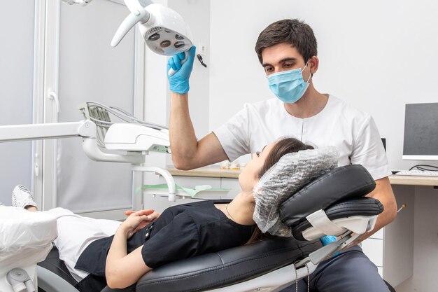 Dentista che regola la lampada dentale nello studio dentistico Dentista che accende la lampada prima del trattamento