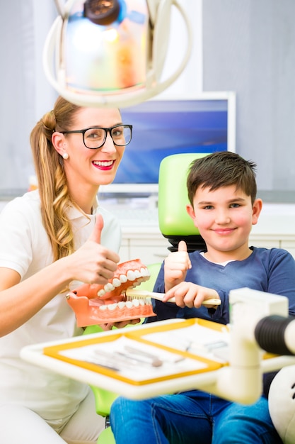 Dentista che spiega il dente di pulizia del ragazzo