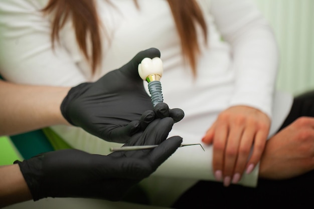 Dentista che spiega il modello dei denti alla paziente femminile. Scatti tecnici su un laboratorio di protesi dentaria.