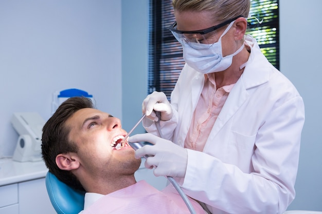 Dentista che tiene attrezzatura medica mentre dà il trattamento al paziente