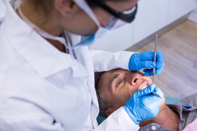 Dentista che tiene gli strumenti mentre esamina l'uomo alla clinica