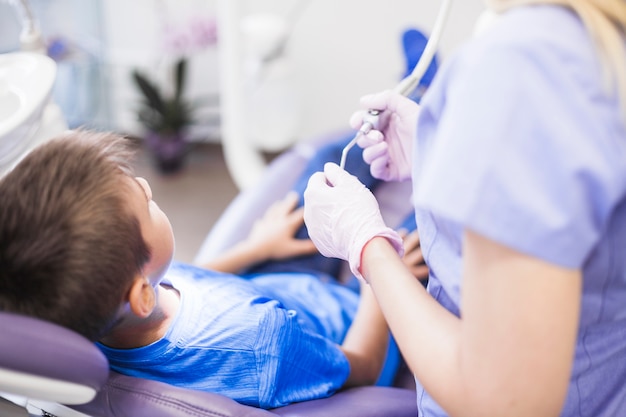 Dentista che tiene lo scalatore ultrasonico vicino al paziente in clinica