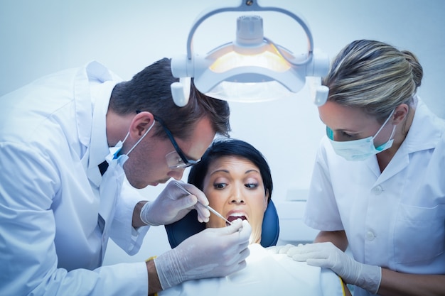 Dentista con l&#39;assistente che esamina i denti dei womans