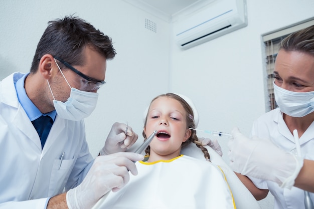 Dentista con l&#39;assistente che esamina i denti delle ragazze