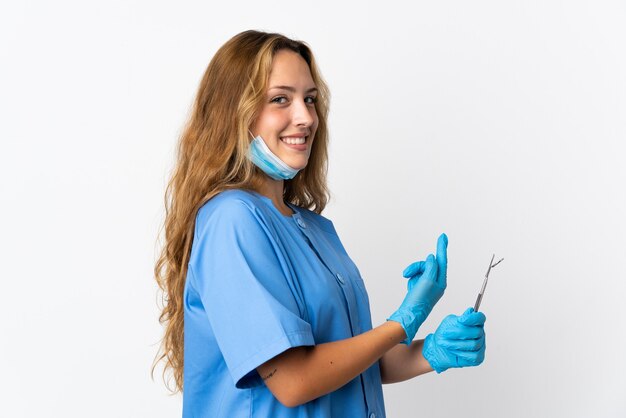 Dentista della donna che tiene gli strumenti isolati che indicano indietro