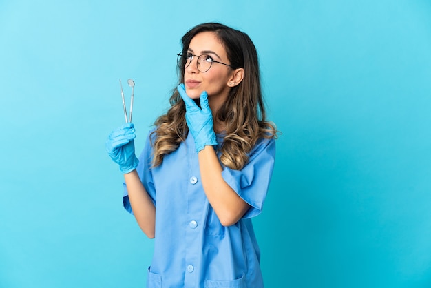 Dentista della donna che tiene gli strumenti sopra lo sguardo isolato mentre sorridente