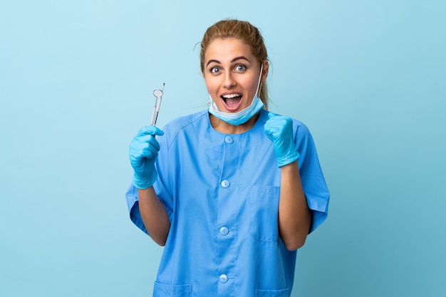 Dentista della giovane donna che tiene gli strumenti isolati per celebrare una vittoria