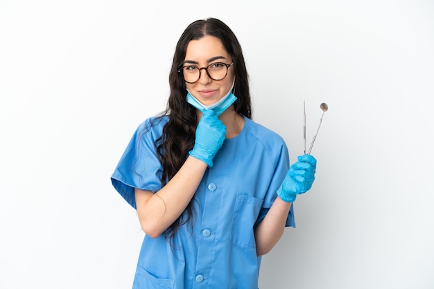 Dentista della giovane donna che tiene gli strumenti isolati sul pensiero bianco del fondo