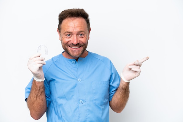Dentista di mezza età che tiene l'uomo che prevede isolato su sfondo bianco che punta il dito di lato