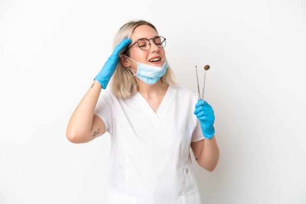 Dentista donna caucasica tenendo gli strumenti isolati su sfondo bianco sorridendo molto