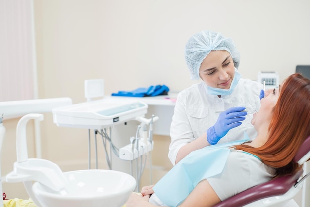 Dentista donna che controlla il suo paziente per la carie Donna dai capelli rossi esaminata da un medico La ragazza farà la salute dei denti