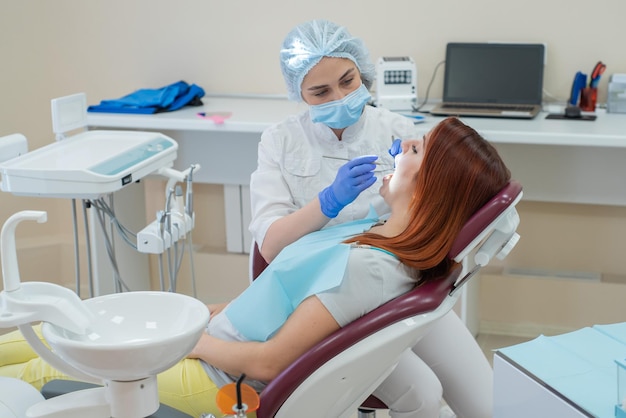 Dentista donna che controlla il suo paziente per la carie Donna dai capelli rossi esaminata da un medico La ragazza farà la salute dei denti
