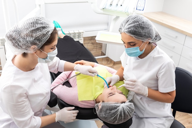 Dentista e assistente che esegue il trattamento dentale nel moderno paziente della clinica odontoiatrica sdraiato su una sedia