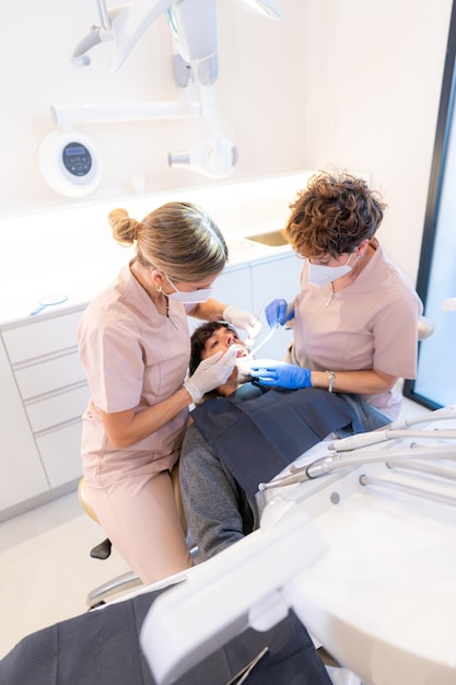 Dentista e assistente che eseguono un controllo della bocca e dei denti su un giovane cliente nella moderna clinica dentale