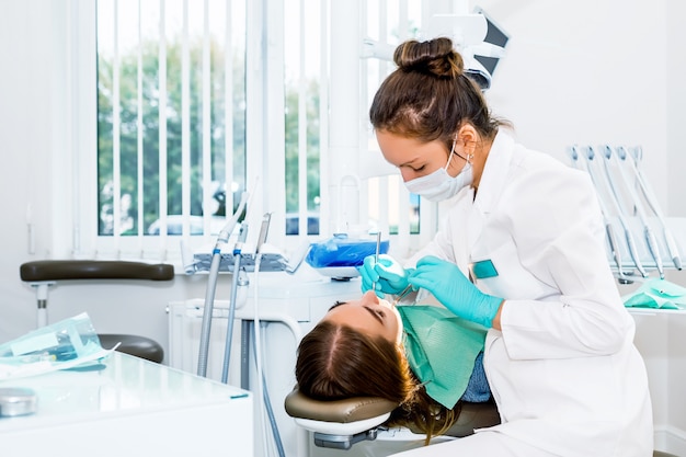 Dentista femminile che controlla i denti pazienti con le parentesi graffe all'ufficio della clinica dentale.