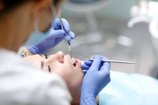 Dentista femminile che controlla i denti pazienti della ragazza