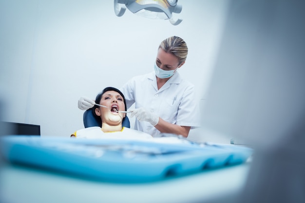 Dentista femminile che esamina i denti della donna