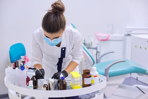 Dentista femminile che lavora con materiali medici e strumenti professionali speciali sul tavolo di lavoro