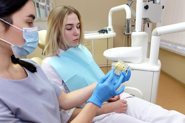 Dentista femminile che mostra un modello di una mascella artificiale a un paziente