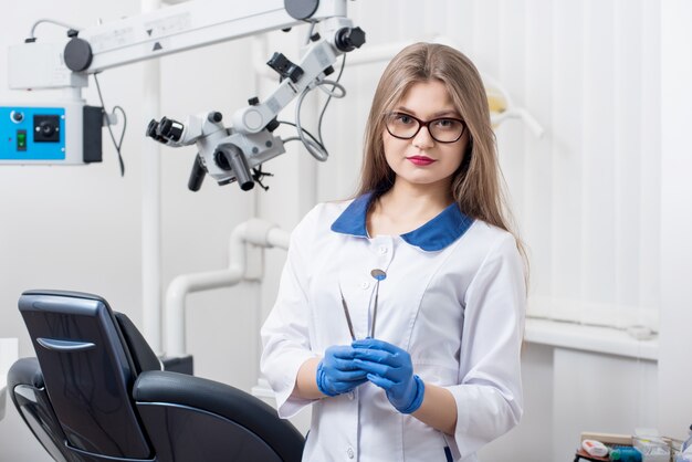 Dentista femminile che tiene gli strumenti dentali all'ufficio dentale di morden