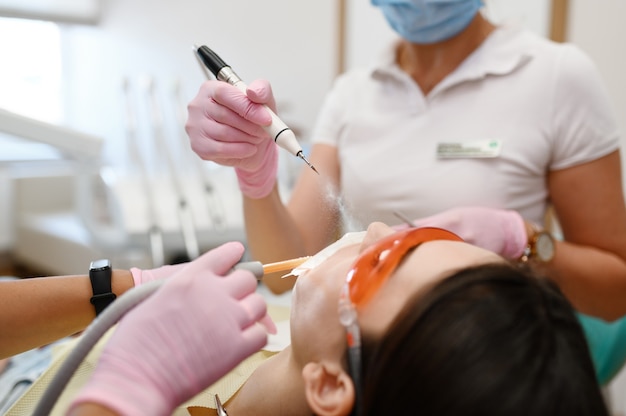 Dentista femminile e paziente, procedura di sbiancamento dei denti in clinica, stomatologia