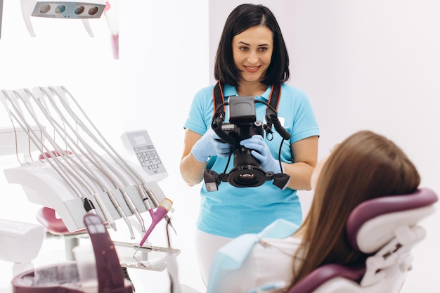 Dentista femminile fotografa i denti del suo paziente su una poltrona odontoiatrica