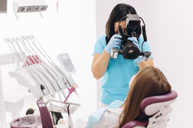 Dentista femminile fotografa i denti del suo paziente su una poltrona odontoiatrica