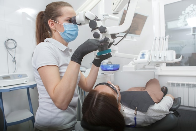 Dentista femminile operante microscopio dentale, trattamento dei denti del paziente